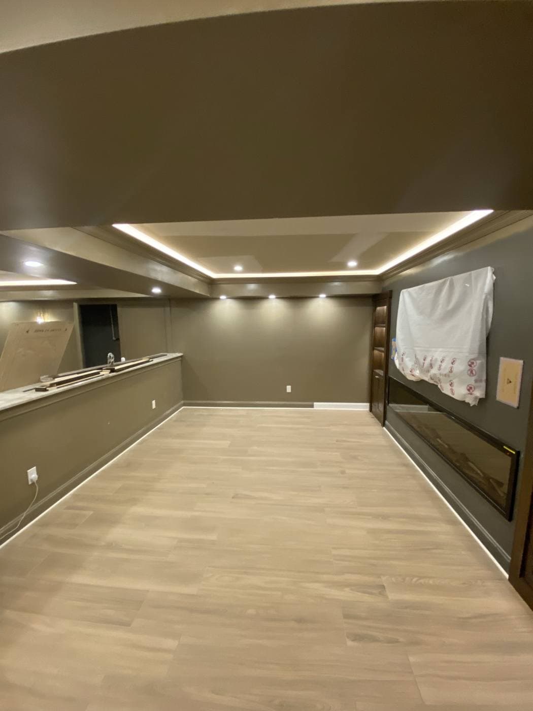 A long room with cove lighting around the ceiling and a continuous lit line running along the base of the walls at floor level.