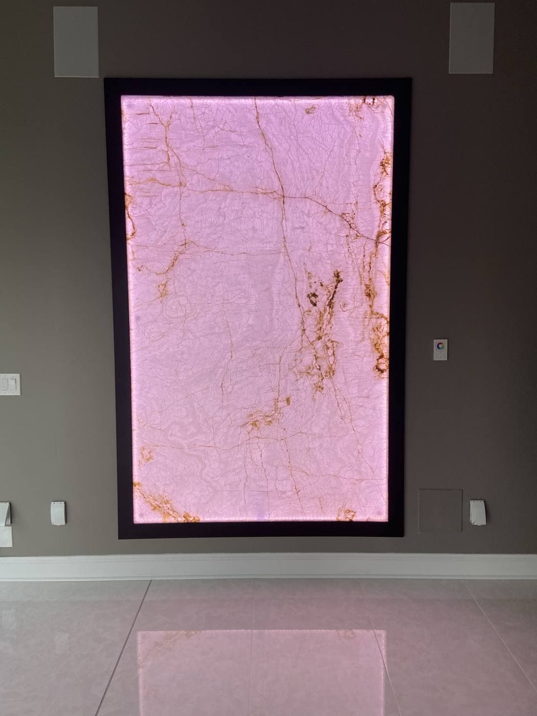 The same backlit stone panel glowing pink, showing the wall on a different colour setting.